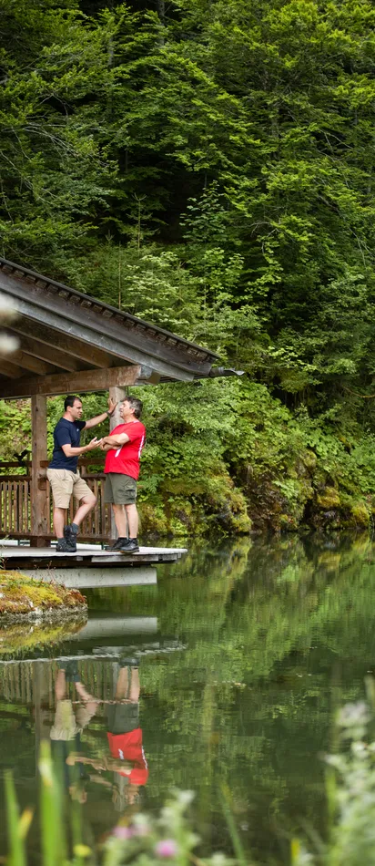 Zwei Männer unterhalten sich auf einer Holzterrasse am See im Wald