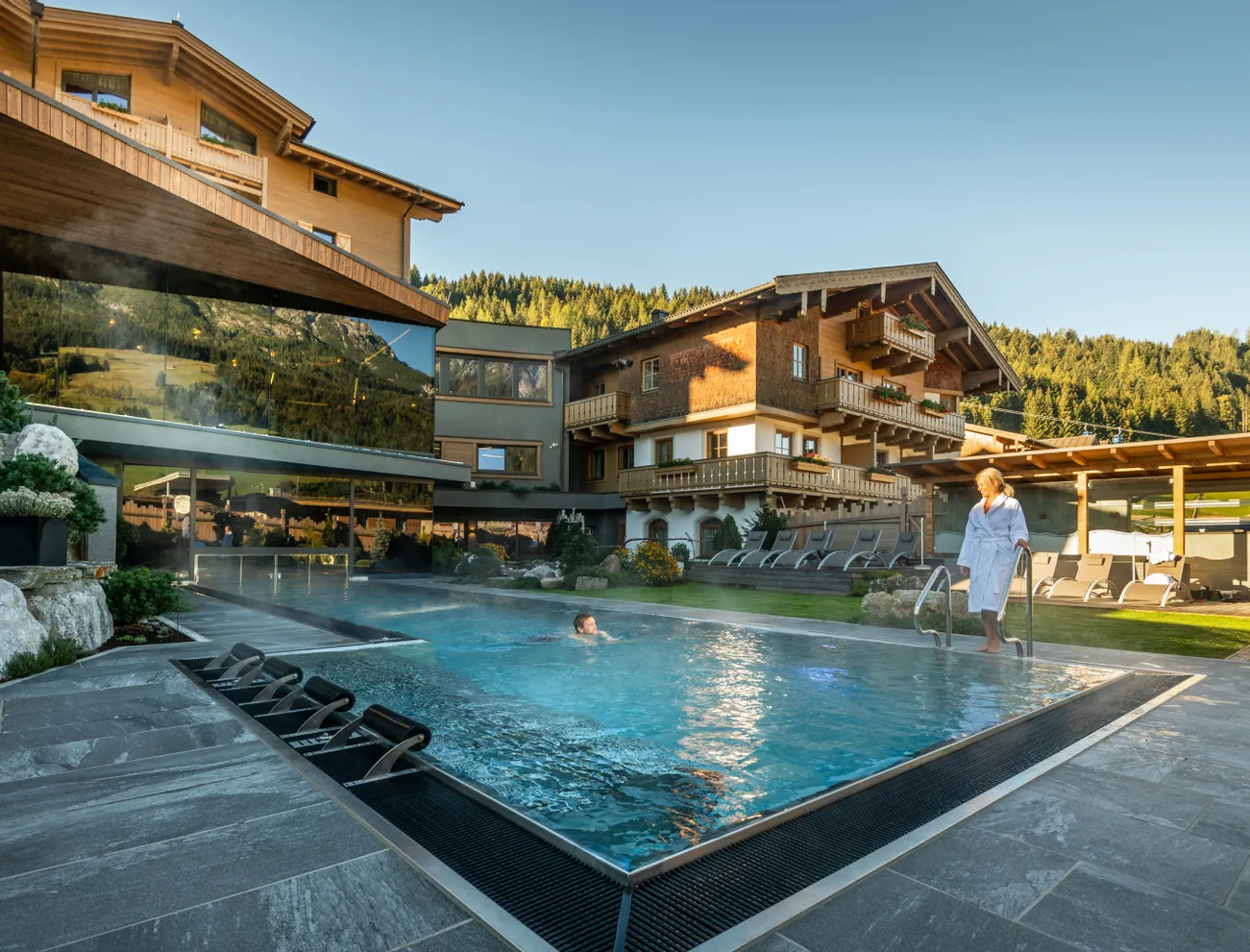 Außenpool eines Wellnesshotels in den Alpen mit Holzchalets und Bergblick