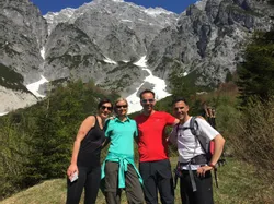 Gruppe von Wanderern auf Bergpfad mit schneebedeckten Gipfeln im Hintergrund