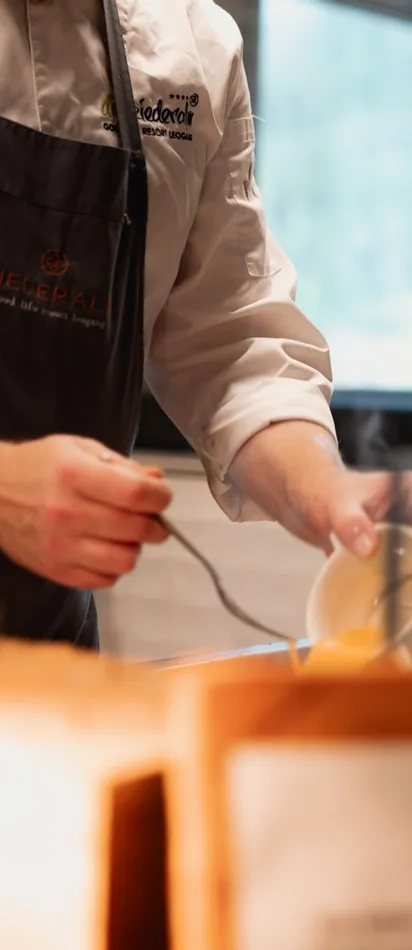 Chef in uniform serving hot soup into a bowl at a restaurant counter