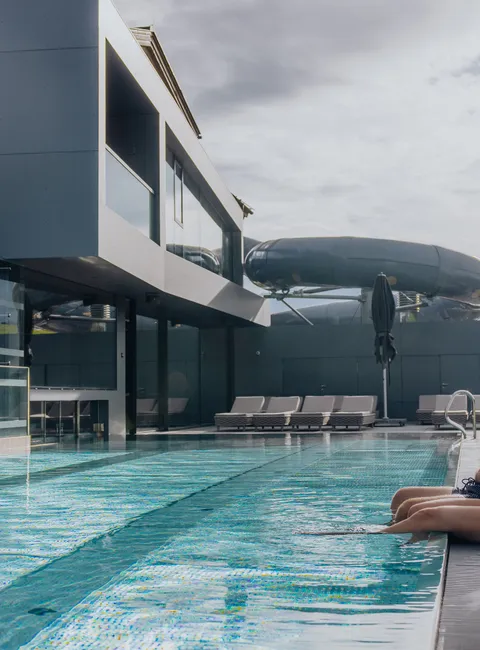 Couple relaxing by the edge of a modern outdoor hotel pool with mountain view
