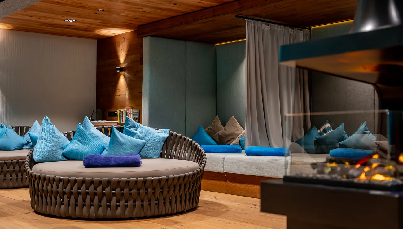 Cozy spa lounge with round loungers, blue cushions, and a modern fireplace