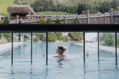 Frau entspannt im beheizten Außenpool mit Bergblick im luxuriösen Spa-Resort