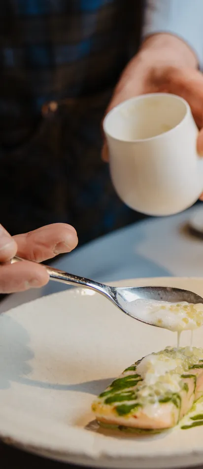 Koch richtet Gourmet-Lachsgericht mit Schaum und Kräutern im Gourmetrestaurant an