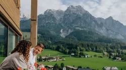 Paar im Bademantel genießt Bergblick vom Balkon im Alpenresort