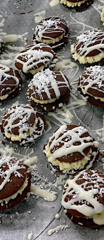 Homemade chocolate sandwich cookies with cream filling and white icing drizzle