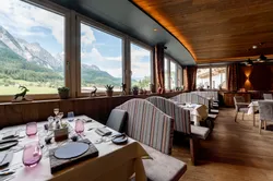 Modernes Restaurant mit Alpenblick durch große Fenster und gemütlichen Sitznischen