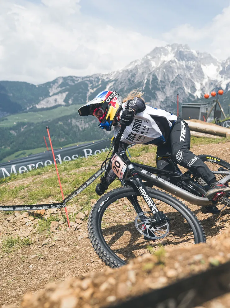 Mountainbiker fährt auf steinigem Abhang bei UCI-Event mit Alpen im Hintergrund