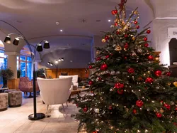 Geschmückter Weihnachtsbaum mit roten und goldenen Kugeln in gemütlicher Hotellobby