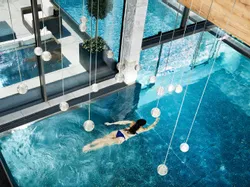 Woman swimming in a luxurious indoor spa pool with modern glass design