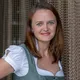Frau in traditionellem bayerischen Dirndl lächelt vor Kettenvorhang