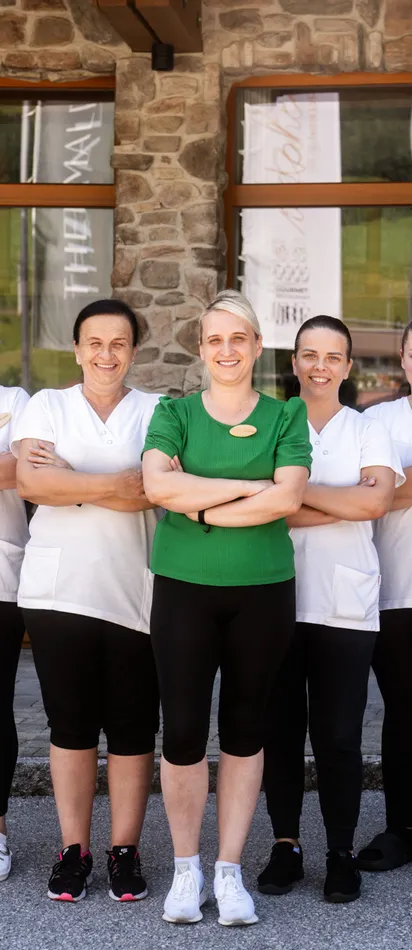 Housekeeping team in uniform standing and smiling in front of a hotel building
