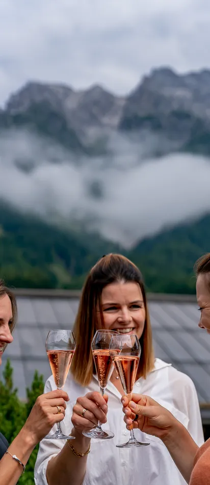 Women toasting with rosé champagne on a terrace with mountain view
