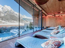 Modern alpine spa lounge with mountain view, large windows and relaxing loungers