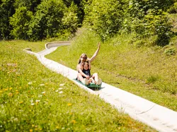 Mutter und Tochter flitzen die Sommerrodelbahn in Saalfelden Leogang hinunter ins Tal. 