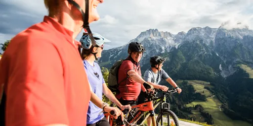 Gruppe von Radfahrern genießt einen Panoramaausblick in den Bergen bei Sonnenschein