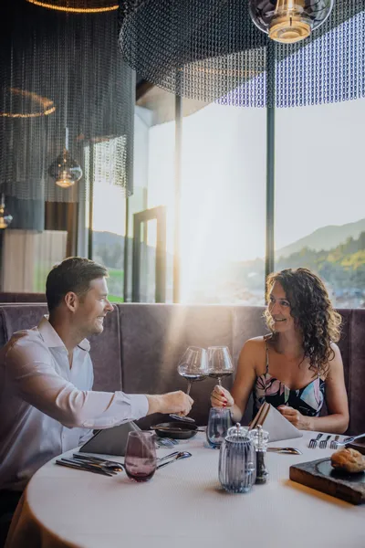 Paar genießt romantisches Abendessen mit Wein in elegantem Restaurant bei Sonnenuntergang