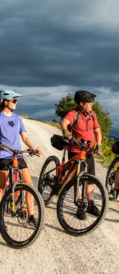 Gruppe Radfahrer auf Bergpfad genießt malerische Landschaft unter bewölktem Himmel