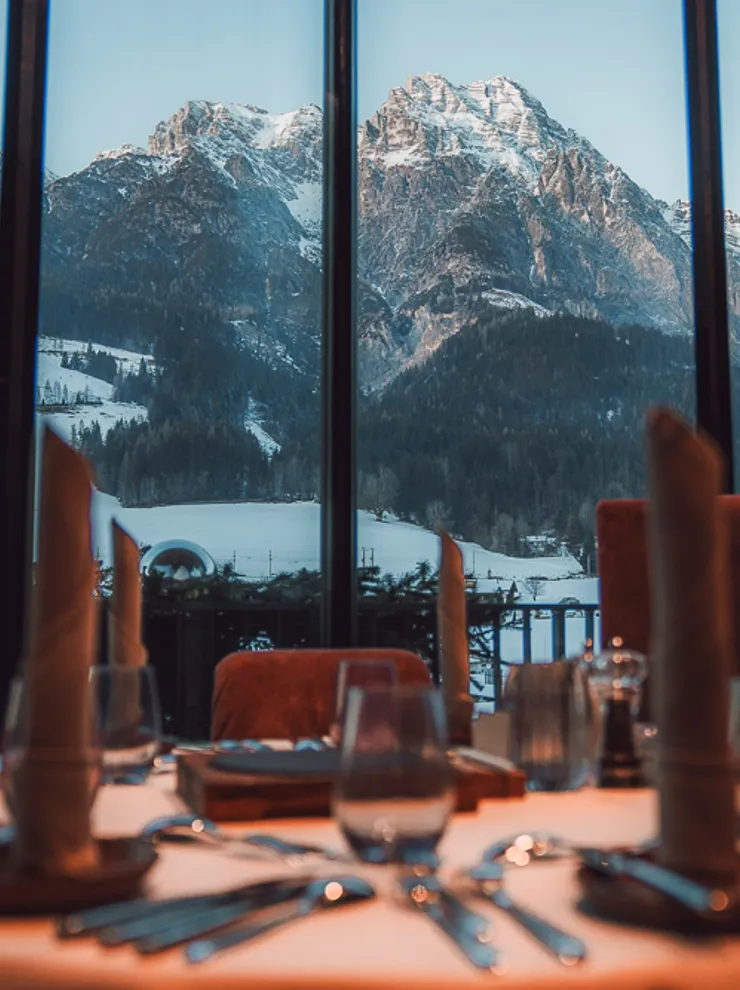 Elegant restaurant table set with view of snow-covered Alps through large window