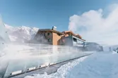 Luxus-Alpenresort mit dampfendem Außenpool und verschneitem Bergpanorama