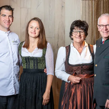 Gruppenporträt von vier Erwachsenen in traditioneller österreichischer Tracht, die drinnen lächeln