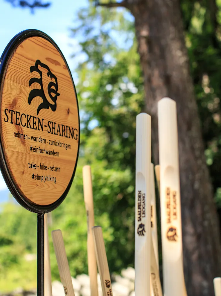 Holz-Wanderstock-Sharing-Station mit Schild in Waldumgebung