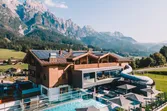 Alpenresort mit Außenpool und Wasserrutsche vor beeindruckender Bergkulisse