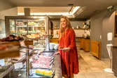 Smiling woman in red dress selecting food at hotel breakfast buffet with meats and pastries