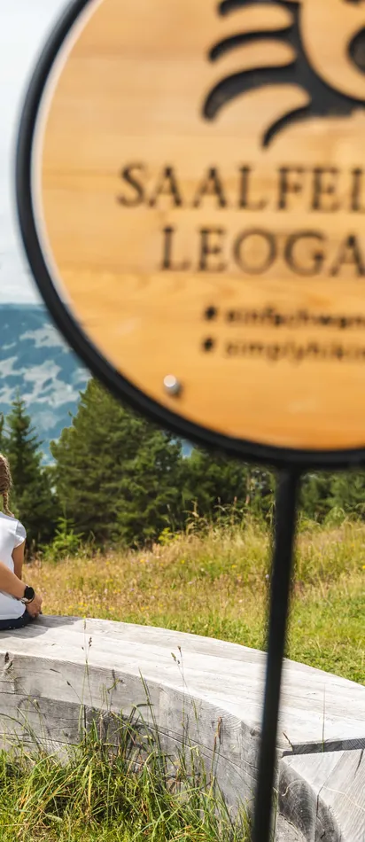 Familie auf Holzbank mit Blick auf die Berge in Saalfelden Leogang beim Wandern