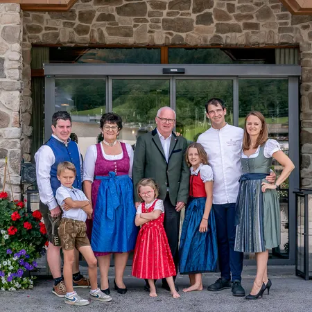 Familie in traditioneller Tracht vor Hotel mit Blumen und Steinfassade