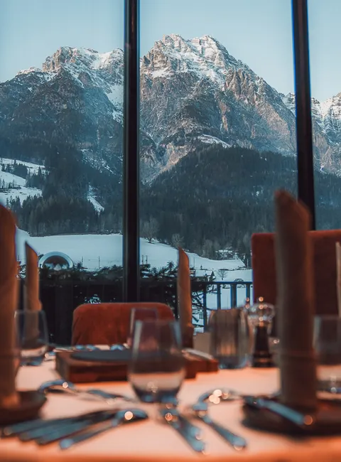 Elegant restaurant table set with view of snow-covered Alps through large window