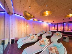 Moderner Spa-Ruheraum mit gepolsterten Liegen, Holzwänden und stimmungsvoller Beleuchtung
