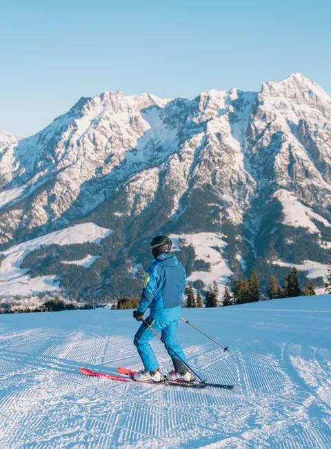 Skier on freshly groomed slope with snow-covered Alps in the background