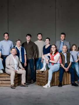 Multigenerational family posing indoors on wooden crates against a gray wall