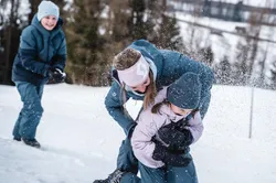 Familie spielt im Schnee mit Schneeballschlacht und Winterkleidung