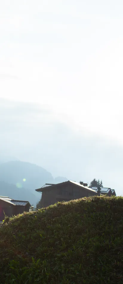 Mountain biker riding uphill at sunset with alpine village and mountains in background