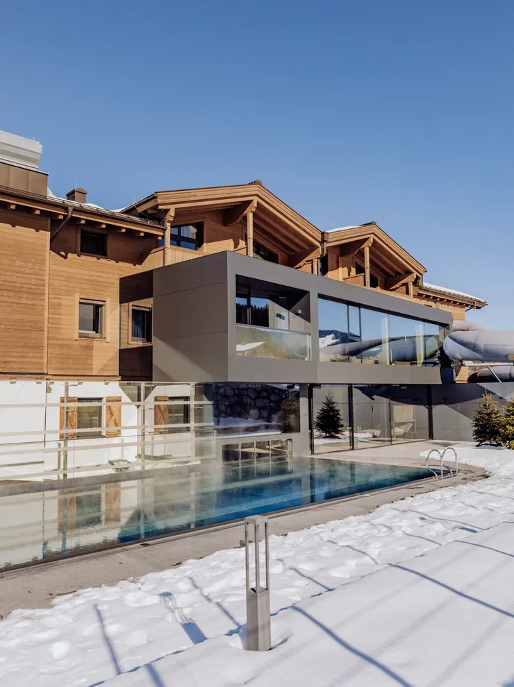 Luxuriöses Berghotel mit Außenpool im schneebedeckten Winterpanorama