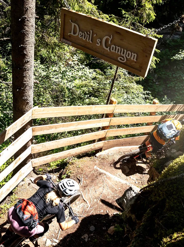 Mountain bikers riding down forest trail at Devil's Canyon with wooden railing