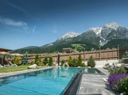 Luxuriöser Außenpool mit Bergblick und gepflegtem Garten im alpinen Wellnessresort