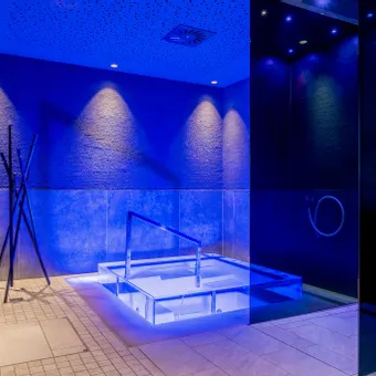 Moderner Innen-Spa-Bereich mit blauer Ambientebeleuchtung und eingelassenem Whirlpool