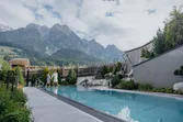 Paar spaziert am Außenpool mit Bergblick im luxuriösen Alpenresort