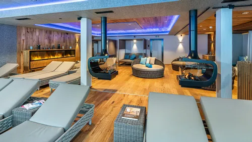 Modern spa relaxation lounge with wicker loungers, fireplaces, and ambient lighting