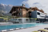 Modernes Wellnesshotel mit Außenpool und Bergblick in alpiner Landschaft