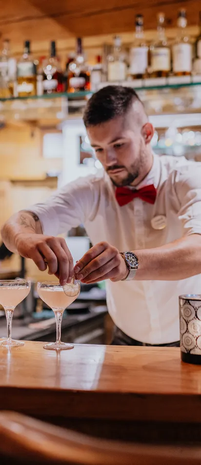 Barkeeper garniert Cocktails an einer Holztheke in einem stilvollen Restaurant