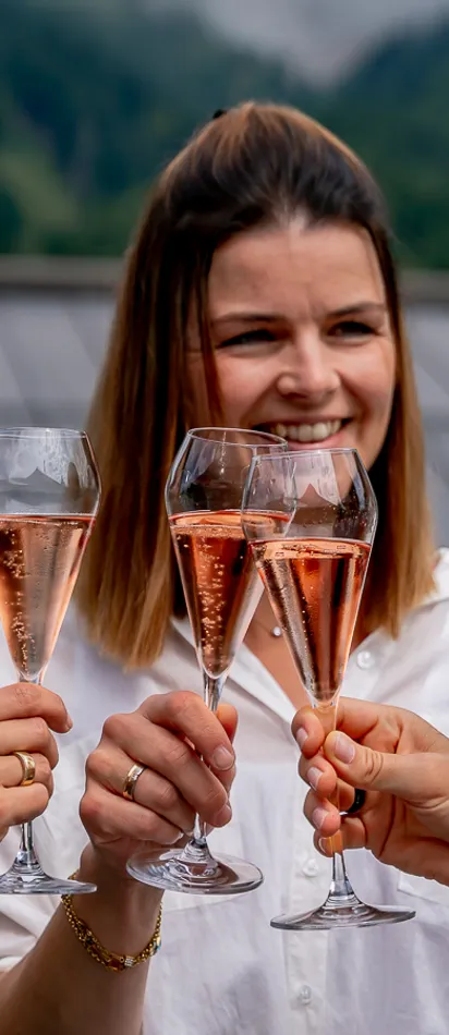 Frauen stoßen mit Rosé-Champagner auf einer Terrasse mit Bergblick an