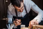 Chef plating gourmet dish on wooden serving cart in fine dining restaurant