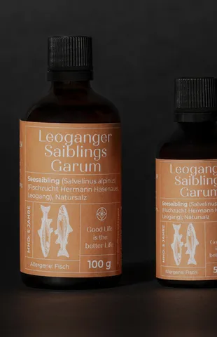 Zwei Flaschen Leoganger Saiblings Garum Fischsauce auf dunklem Hintergrund