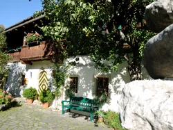 Traditional alpine house with wooden balcony, flower pots, and a cobblestone courtyard