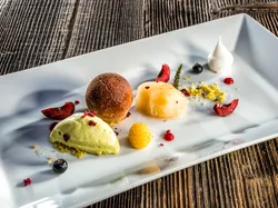 Gourmet dessert with scoops of ice cream and sorbet, berries, and meringue on white plate