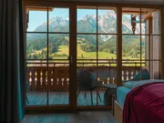 Gemütliches Hotelzimmer mit Bergblick durch Holzfenster im Alpenraum